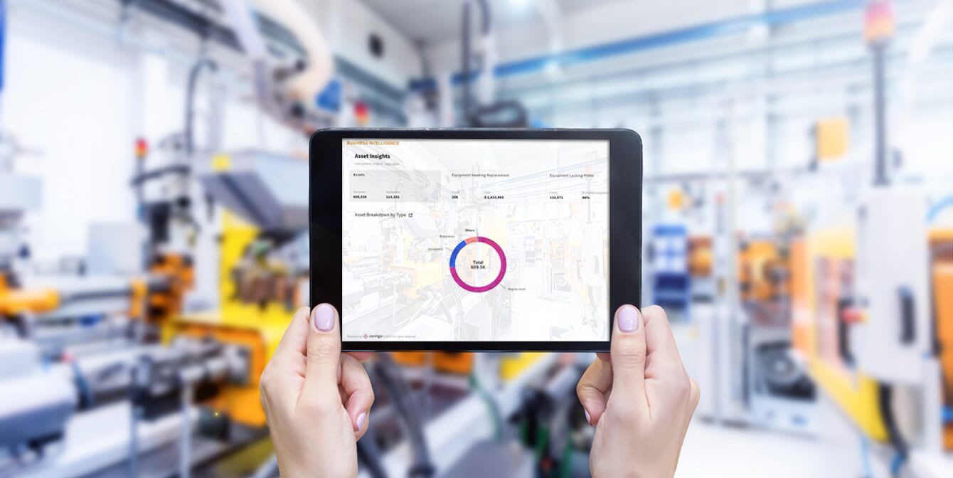 facilities manager in warehouse holds tablet with asset insights dashboard