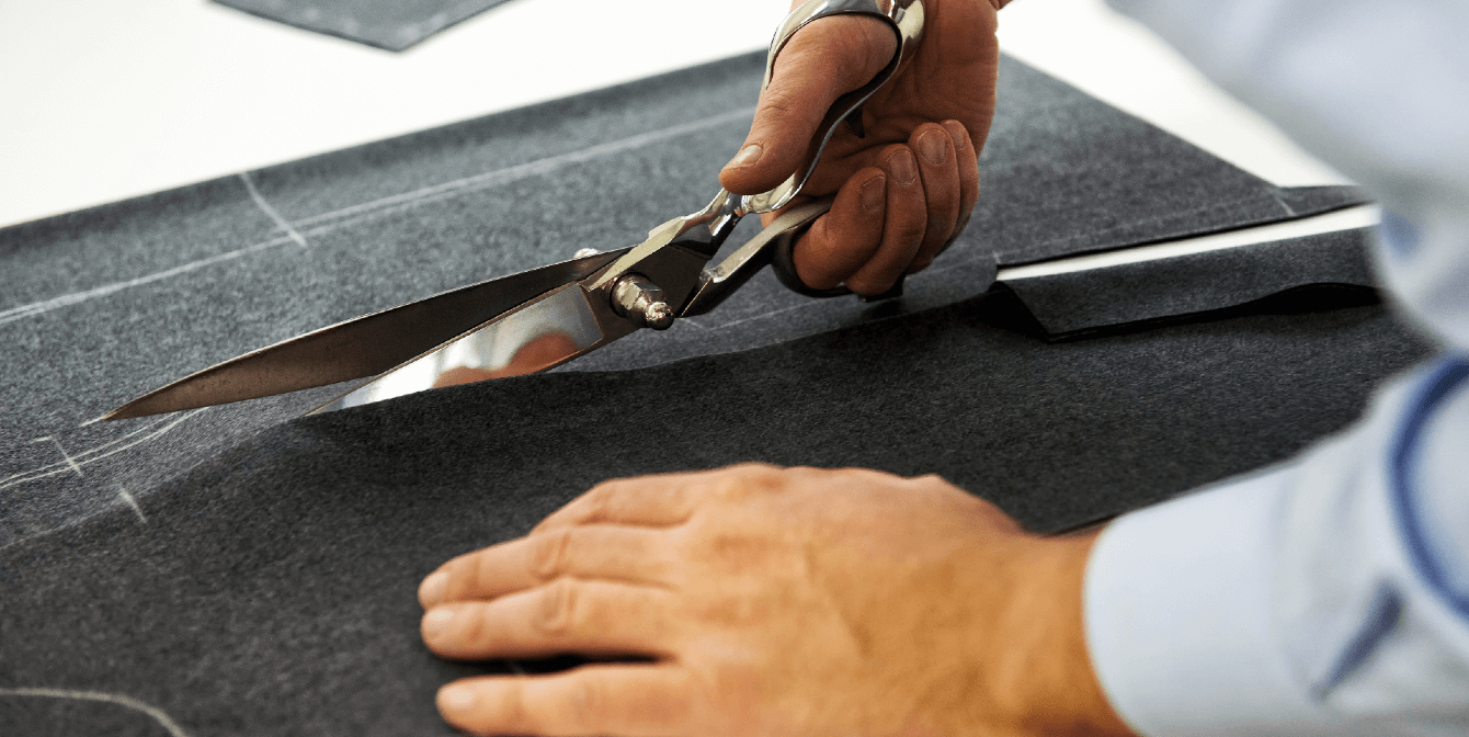 CuttingSpaceinCRE | JLL Technologies a man is cutting a piece of fabric on a work table